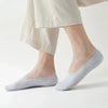 A pair of light gray silicone grip no-show socks worn on a person's foot.