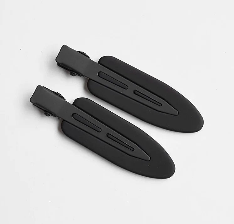 A set of two matte black resin side hair clips lying on a white background.