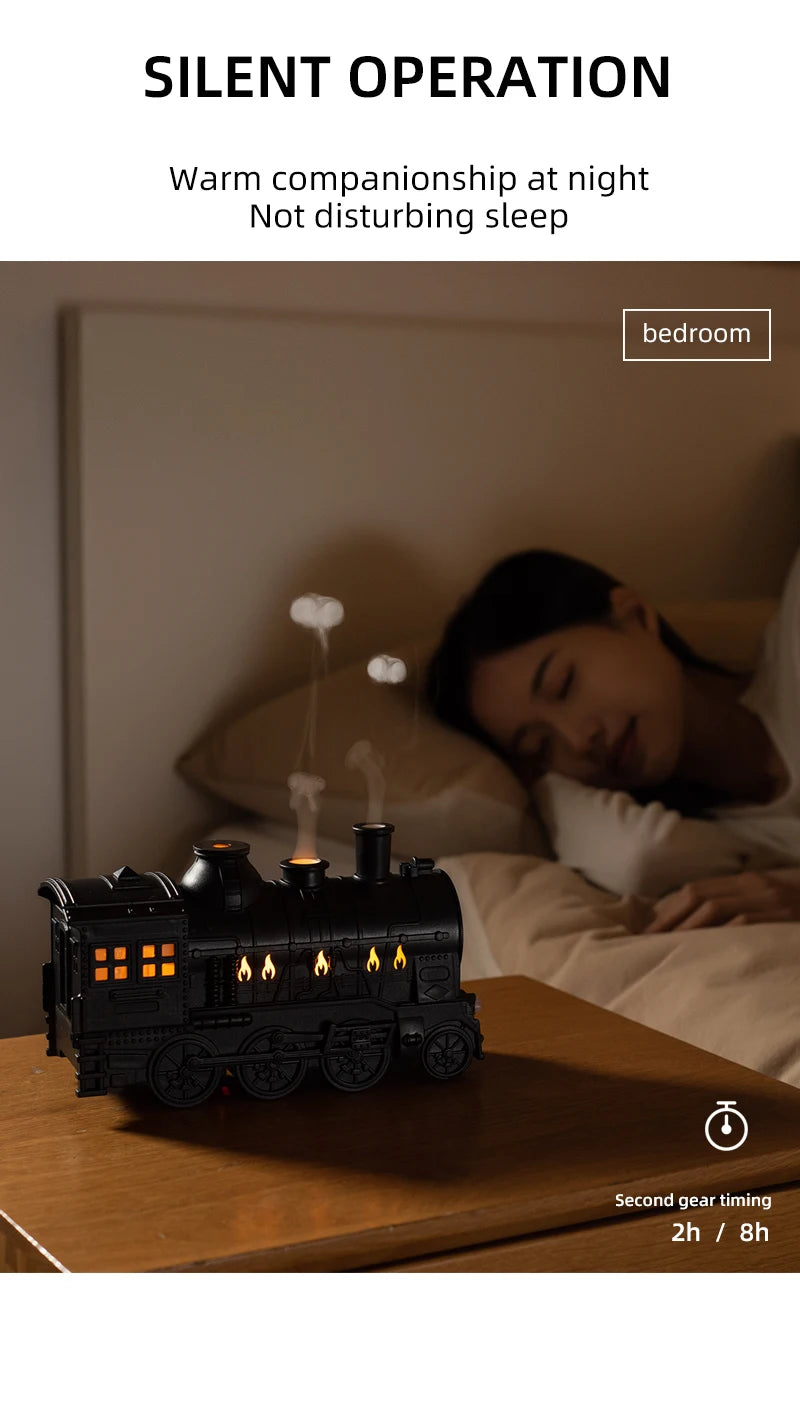 Difusor de aromaterapia en forma de locomotora vintage negra sobre madera, junto a una persona durmiendo en el dormitorio.