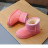 A pair of pink suede ankle boots with a fluffy cream lining resting on brown paper.