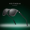 Eine dunkelgraue Veithdia Sonnenbrille, präsentiert vor dunkelgrünem Hintergrund.