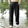 A person wearing dark gray men's cotton linen casual jogger pants standing outdoors.