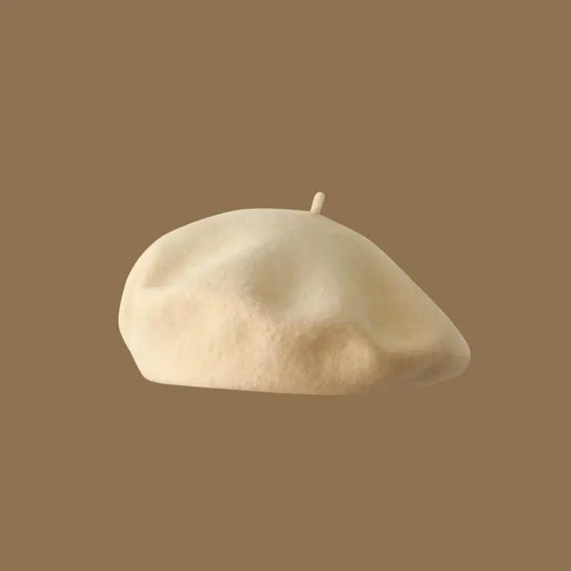 A light beige wool beret hat resting on a plain brown background.