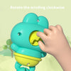 A hand rotates the winding mechanism of a teal floating clockwork frog bath toy.