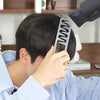 A man is using a gray volumizing wide-tooth styling comb with a seam covering design on his hair.