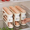 Beige rullende eggoppbevaringsholder med tre nivåer for brune egg i en kjøleskuff.