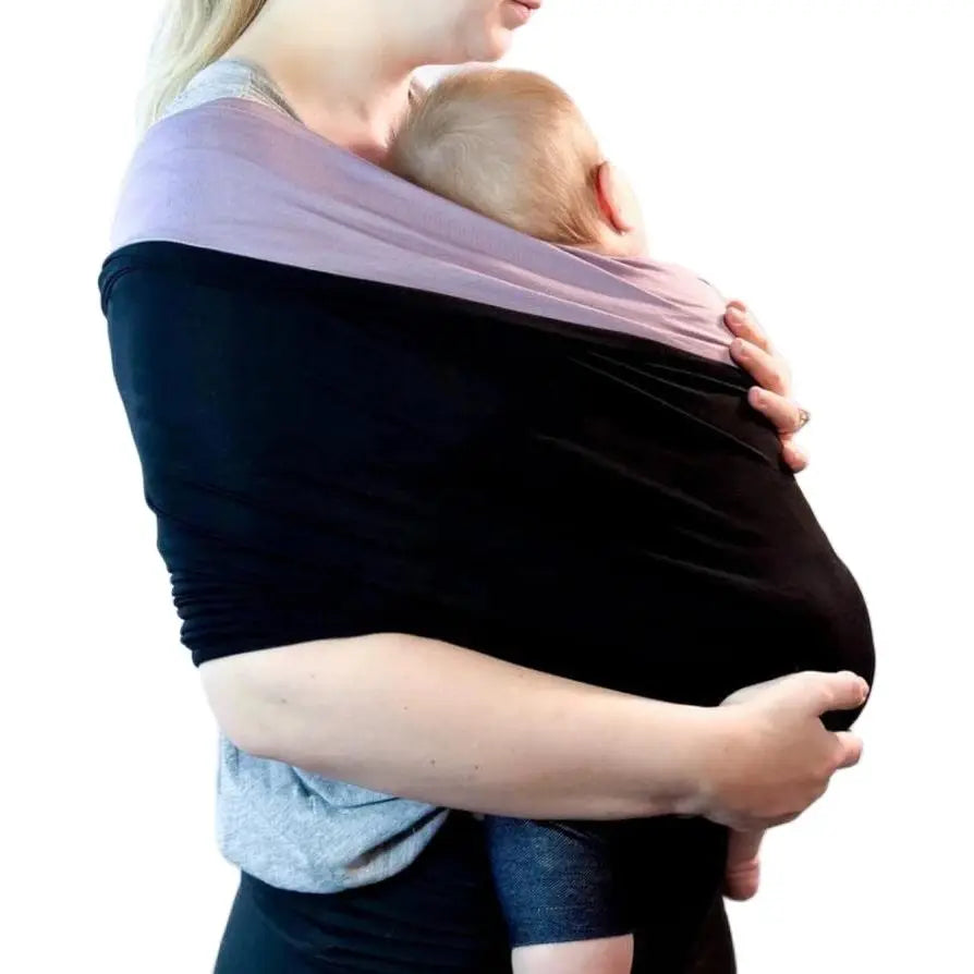 En kvinne i svart topp holder en baby i en myk bæresjal.