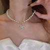 A close-up of an elegant necklace featuring a heart pendant suspended from a strand of simulated pearls.