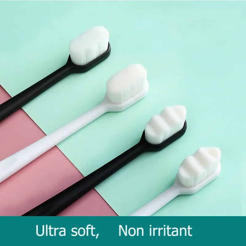 A collection of white and black ultra soft toothbrushes displayed on a light mint green background.
