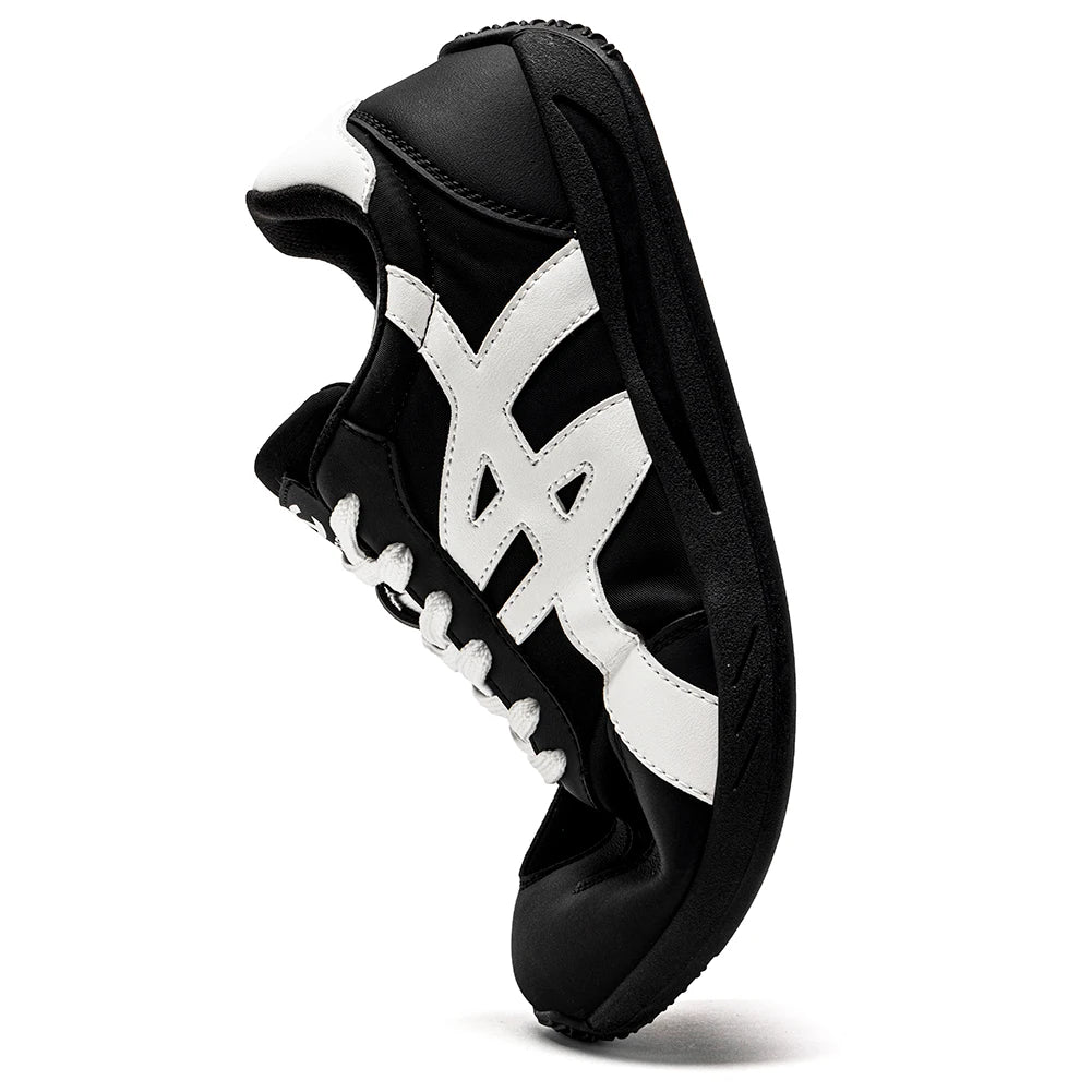 Minimalistischer Sneaker in Schwarz-Weiß von der Seite, mit betonter weiter Zehenbox und Sohle.