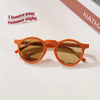 A pair of orange sunglasses with amber lenses resting on a white surface.