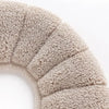 Close-up of a beige knitted soft acrylic toilet seat cover with ribbed texture.