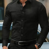 A man wearing a black long-sleeve formal shirt and dark trousers, standing outdoors.