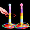 A hand is holding a colorful ring toss game with stacking cups and rings on a black background.