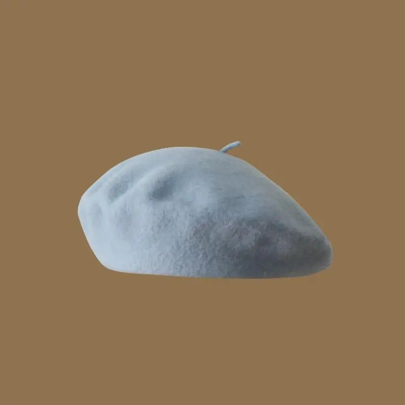 A light blue classic wool beret hat resting on a plain brown background.