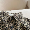 A close-up of a beige and black leopard print denim shirt worn casually.