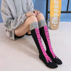Schwarze Overknee-Socken mit rosa Streifen und grauen Bündchen auf weißer Fläche.
