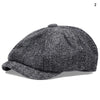 A dark gray vintage newsboy cap with a textured herringbone pattern shown in profile.