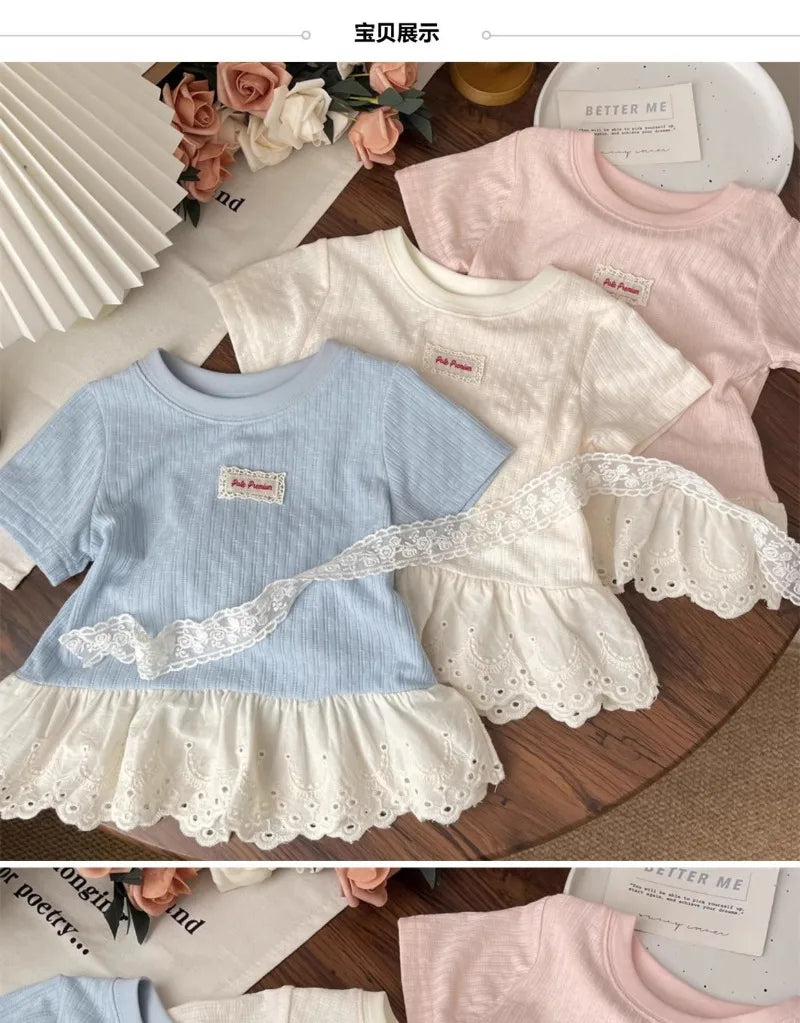 A light blue short sleeve cotton tee with white lace trim and a ruffled hem, displayed on a wooden surface.