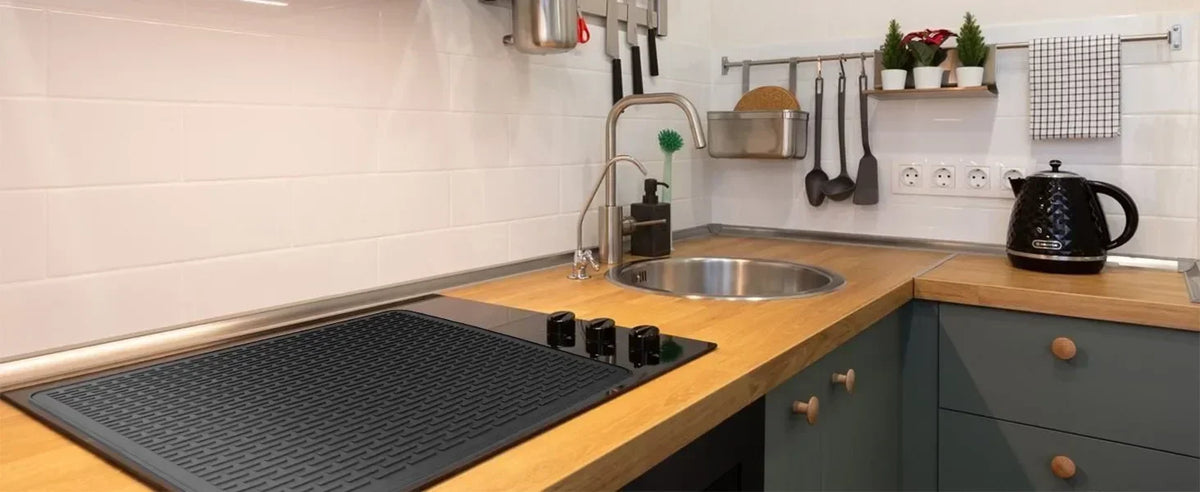 A silicone stove protector mat is placed on a wooden countertop in a kitchen setting.