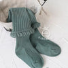 A pair of sage green ribbed cotton tights with a delicate lace cuff displayed on a white background.