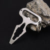 A stainless steel multitool keychain with a bottle opener is resting on a rough gray rock.