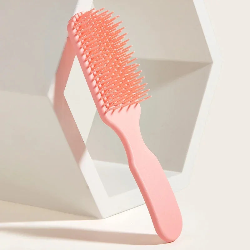 Peine desenredante rosa de 9 púas para masaje capilar sobre superficie blanca.