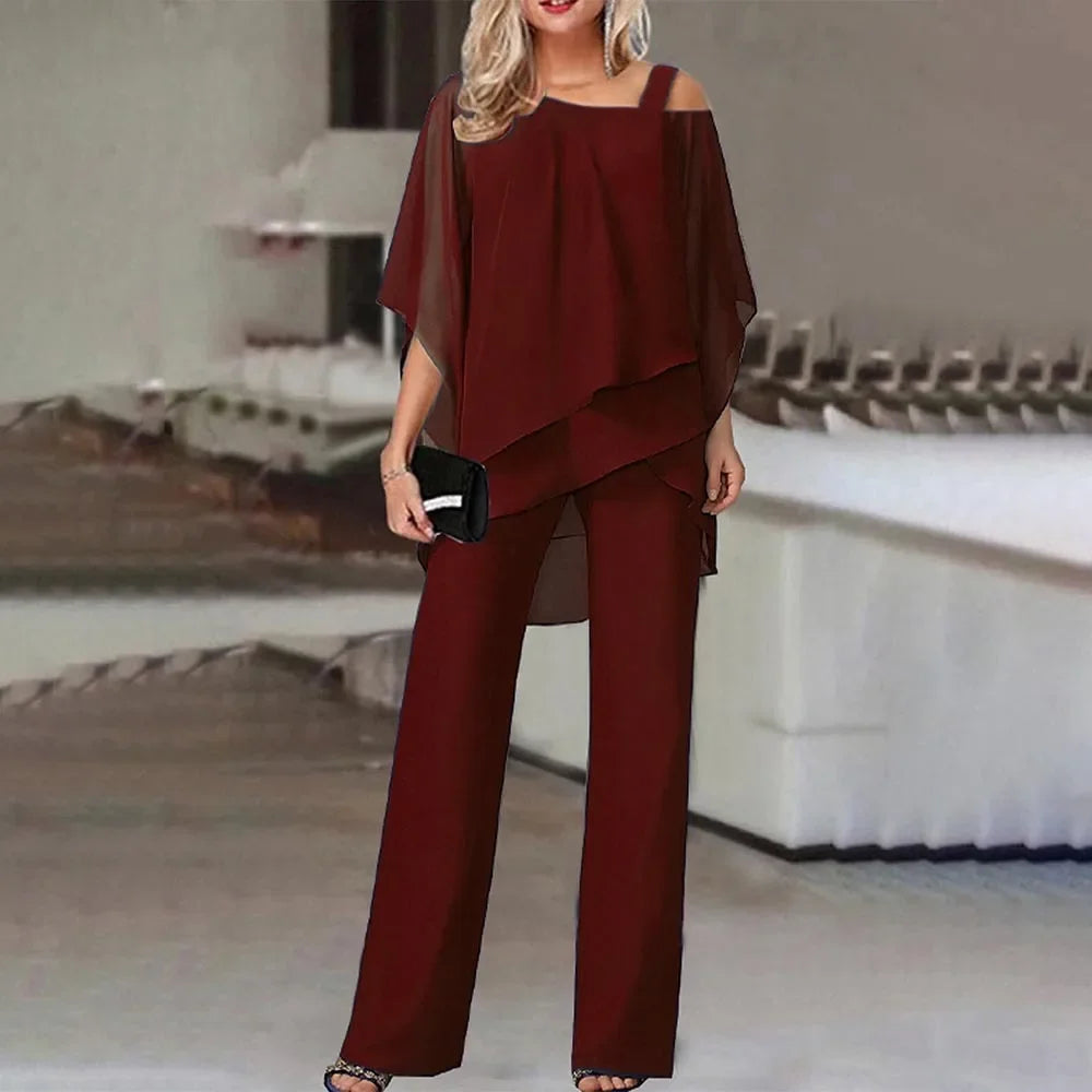 En kvinne modellerer et rødbrunt to-delt sett med off-shoulder topp og brede bukser.