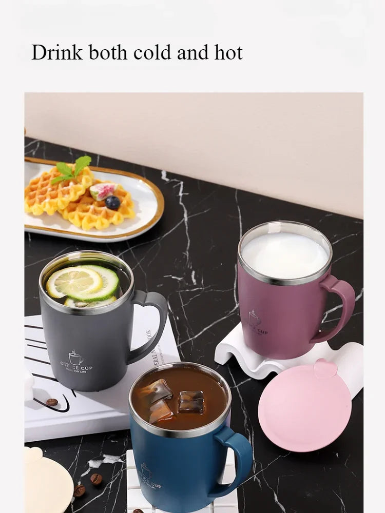 A pink insulated travel mug filled with a light beverage sits next to a dark blue mug and a pink lid on a black marble surfac
