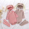 A pink baby bunny romper set includes a matching hat and socks laid out on white fabric.