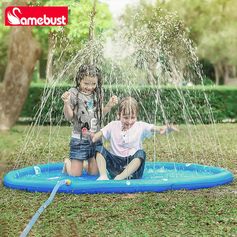 Two children are playing with an inflatable water sprinkler mat outdoors on the grass.