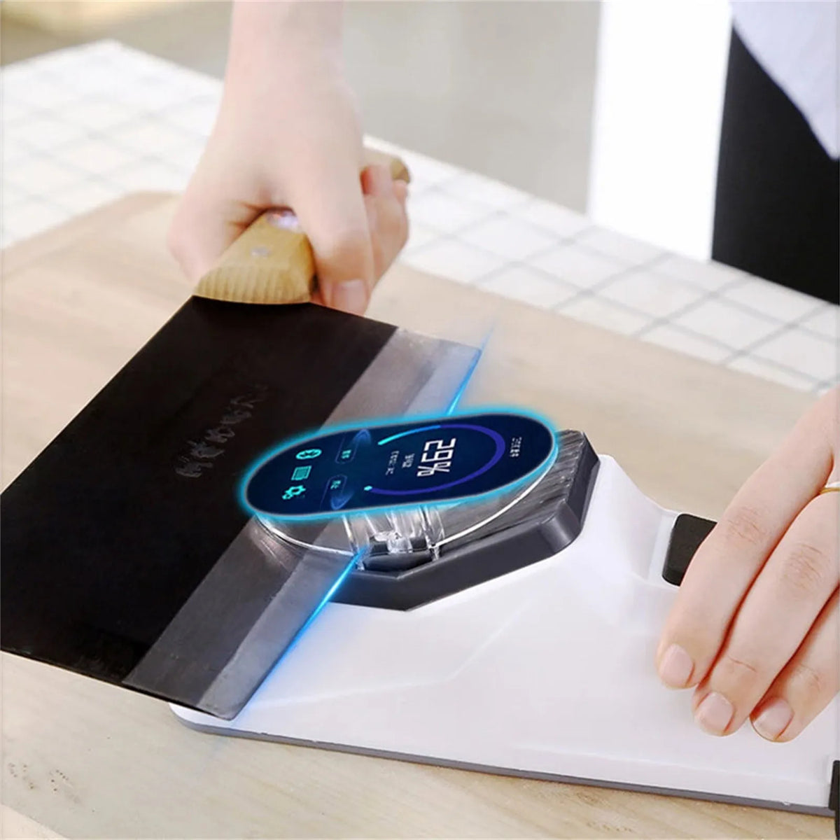 A hand is using an electric knife sharpener with a protective cover to sharpen a blade.
