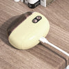 A beige electric nail clipper and grinder with a clear top is resting on a wooden surface.