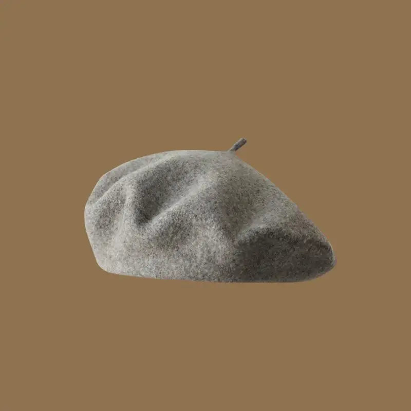 A close-up view of a classic wool beret hat in a light gray color.