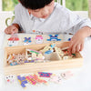 A child is assembling a wooden puzzle featuring bear figures and clothing items for a Montessori dress-up activity.