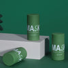 A green cylindrical mask product is displayed on a white block against a dark green background.
