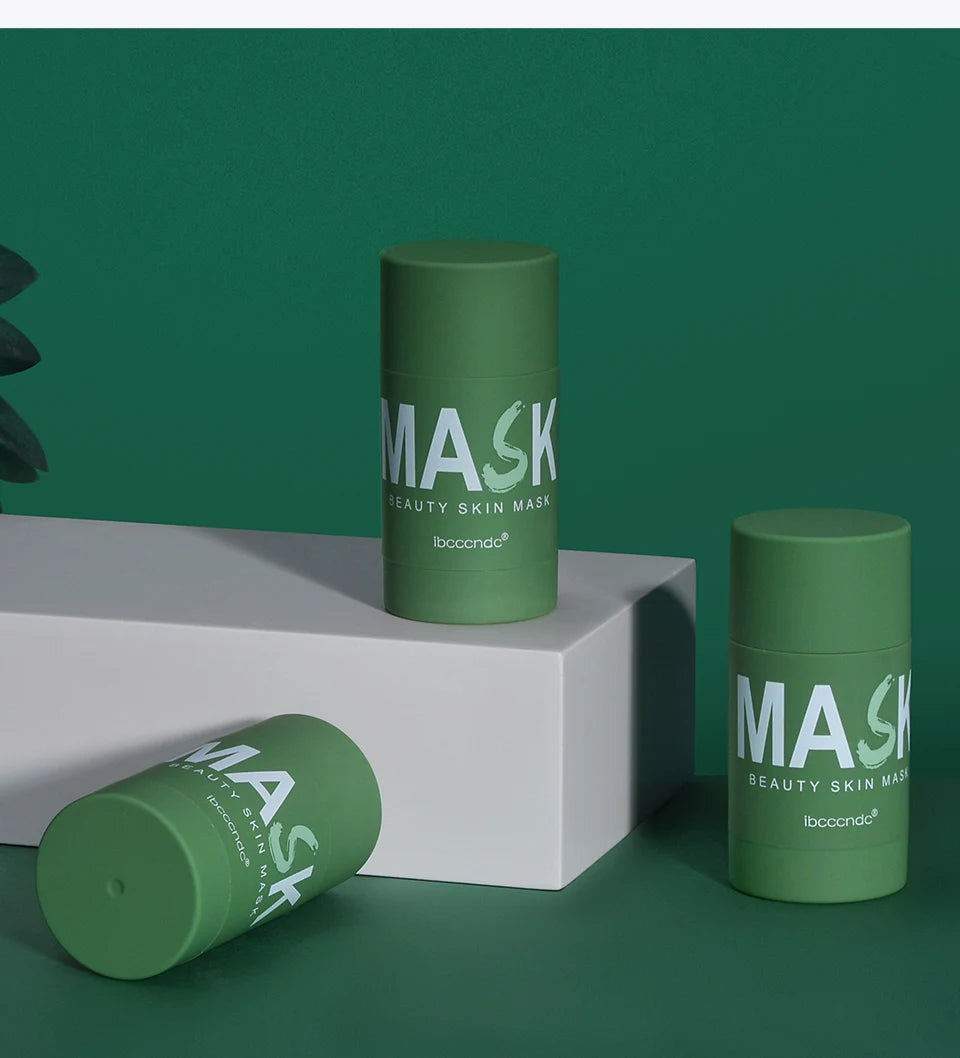A green cylindrical mask product is displayed on a white block against a dark green background.