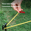A hand adjusts the length of a yellow rope with a red tensioner on green grass.
