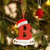 Rød glitrende akrylbokstav B med personlig melding hengende på juletre.