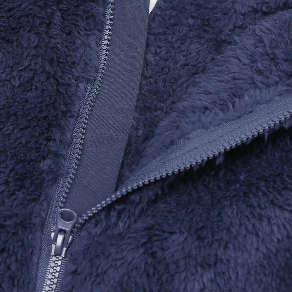 Close-up of a dark blue fuzzy fleece garment with a visible zipper detail.