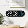 A large digital wall clock displaying time, date, and temperature on a white wall.