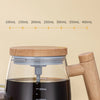 A clear glass mug filled with dark liquid is shown next to a wooden handle, demonstrating various scale capacity markings.