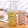 A stack of five double-sided cleaning sponges in yellow and pink colors are shown on a wooden surface.