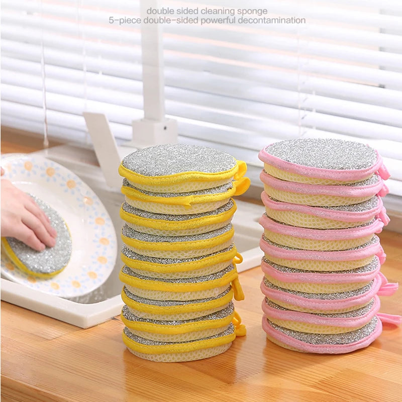 A stack of five double-sided cleaning sponges in yellow and pink colors are shown on a wooden surface.