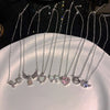 A display of silver crystal bow angel wings heart pendant necklaces arranged on a white plate.