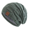 A close-up of a women's slouchy knit beanie in olive green with a multicolor pattern and a gray sherpa lining.