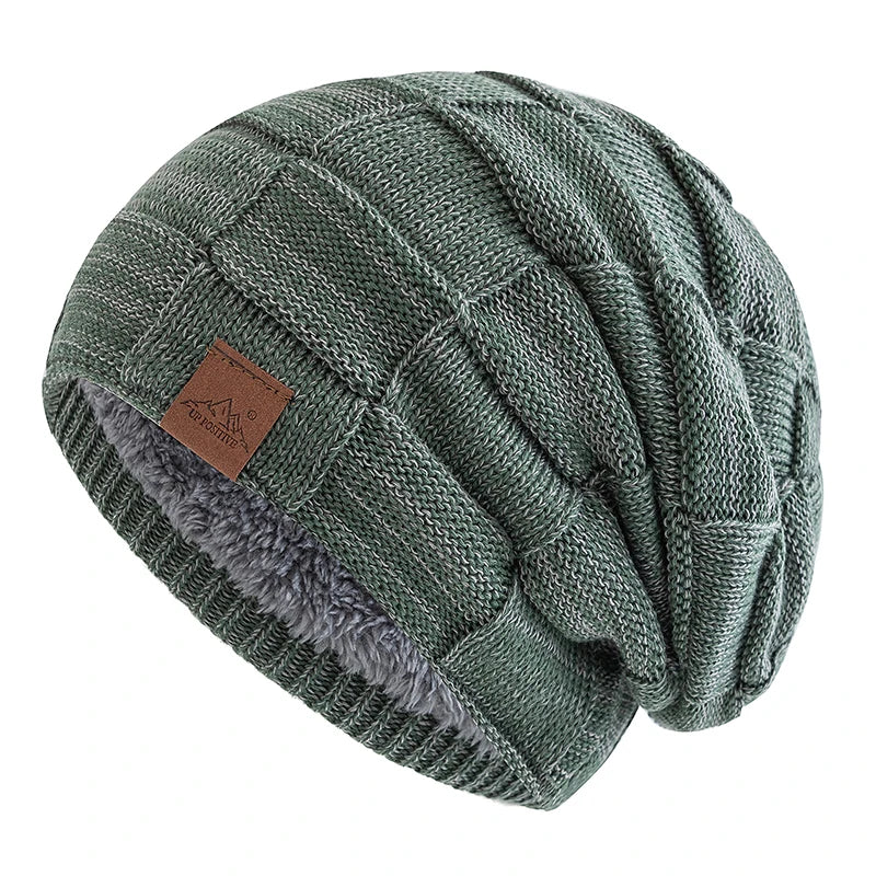 A close-up of a women's slouchy knit beanie in olive green with a multicolor pattern and a gray sherpa lining.