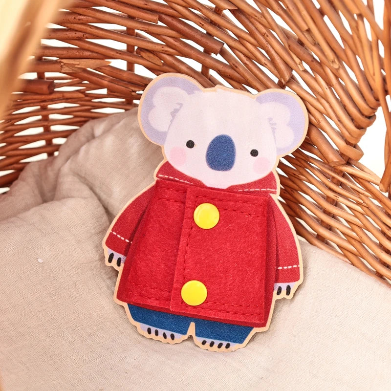 A wooden Montessori busy board featuring a stuffed elephant character in a red coat and blue pants.