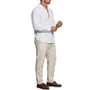 A man wearing a white long sleeve button-down shirt and beige trousers.