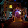 A house decorated for Halloween with spooky window clings and glowing lights on the entrance.
